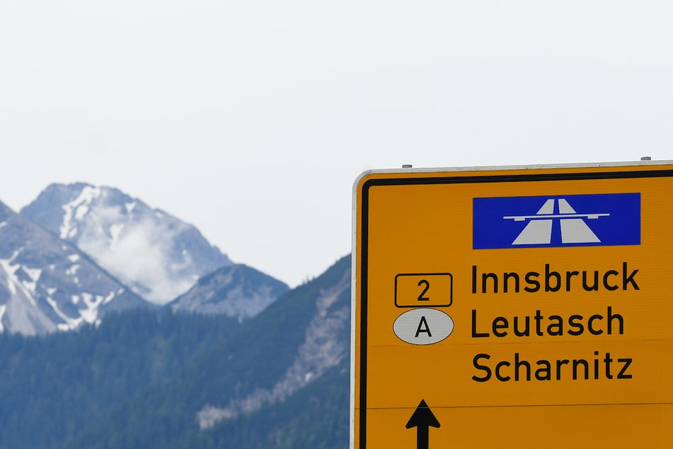 Ein Schild zeigt auf der Landstraße den Weg Richtung Innsbruck in Österreich.