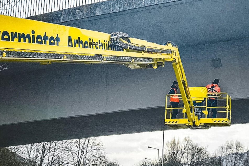 Arbeiter treffen Vorbereitungen für die spätere Einrichtung eines Messsystems an der Bahnbrücke von Bad Schandau.