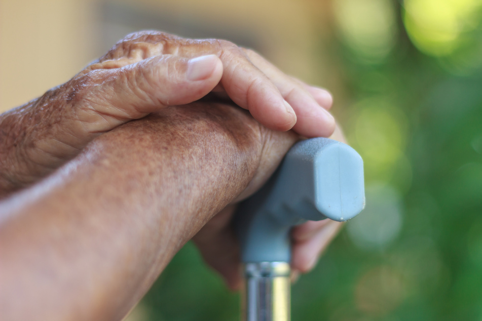 An elderly person is supported by an assistant. (stock image)