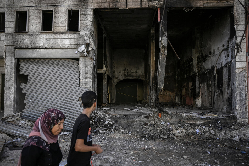 A Palestinian woman and a boy walk among destruction at the Jenin camp in the West Bank.