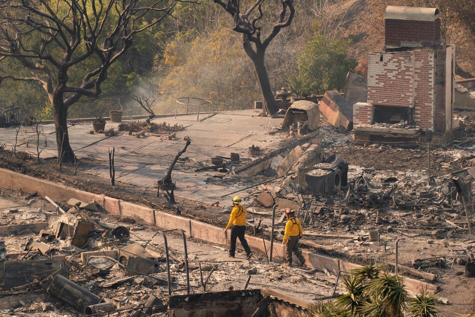 Firefighters survey the remains of homes following the Palisades Fire in the Pacific Palisades neighborhood in Los Angeles, California, on January 10, 2025.