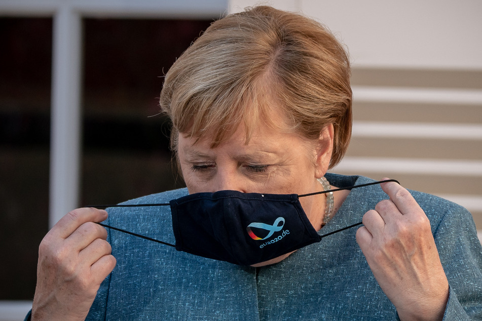 Bundeskanzlerin Angela Merkel (66, CDU), nimmt ihre Maske ab.