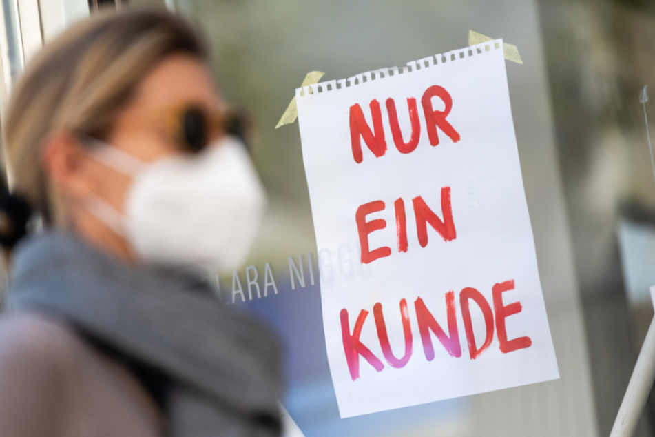 München: Eine Frau mit Nase-Mund-Schutzmaske geht an einem Geschäft vorbei.