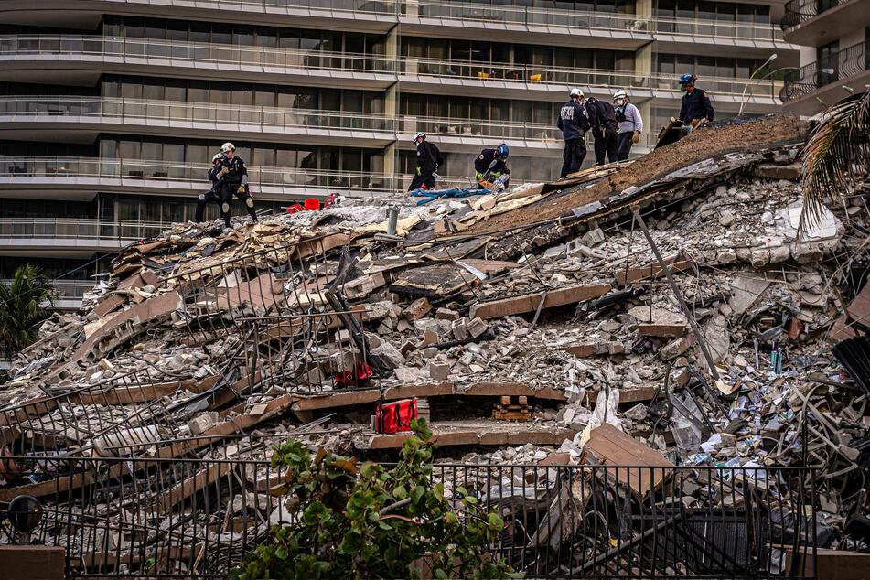 Members of the South Florida Urban Search and Rescue team work in the rubble of the partially collapsed 12-story condo building in Surfside, Florida.