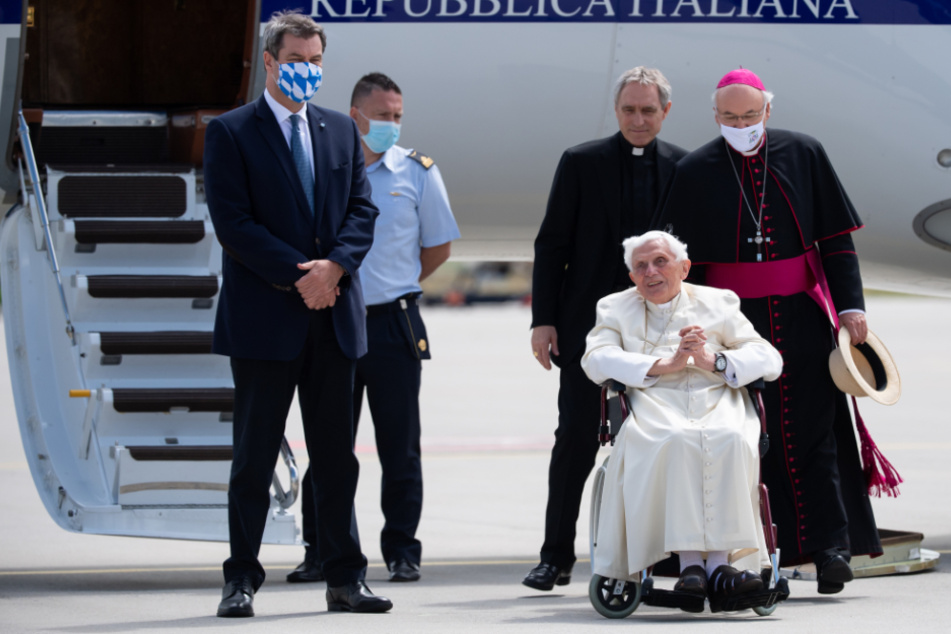 Markus Söder (l-r im Vordergrund, CSU), Ministerpräsident von Bayern, Georg Gänswein, Privatsekretär von Benedikt XVI., der emeritierte Papst Benedikt XVI. und Rudolf Voderholzer, Bischof von Regensburg, stehen am Flughafen München.