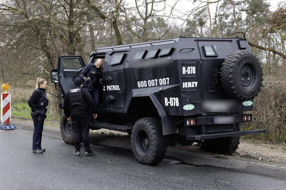 Polizisten untersuchen den gepanzerten Geländewagen, mit dem die Truppe unter anderem angerückt war.