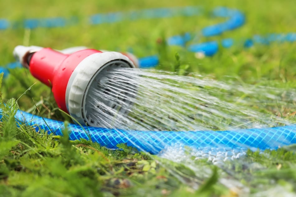 Mit einem Wasserschlauch lässt sich eine Mülltonne ausspülen.