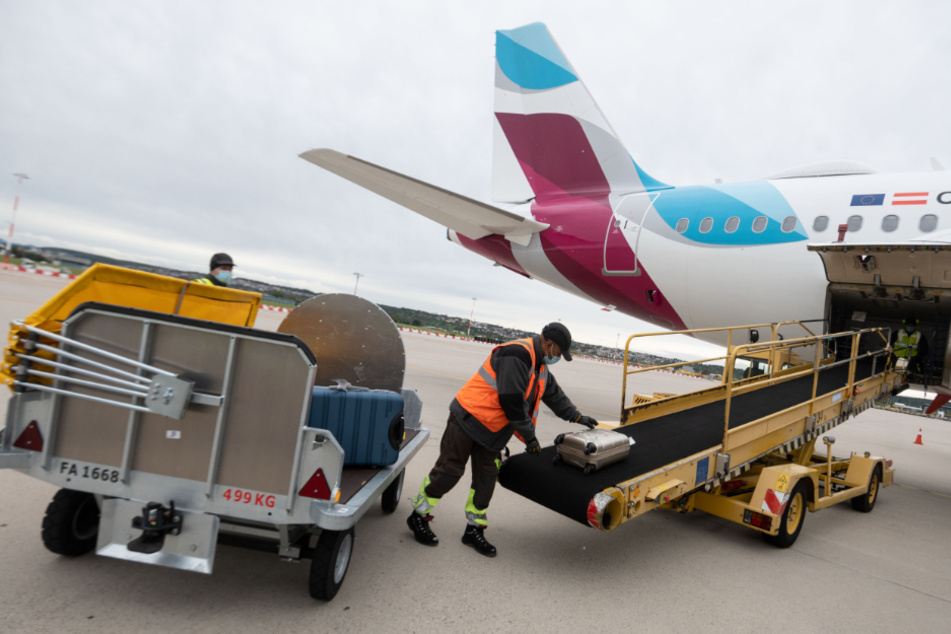 Ein Arbeiter lädt auf dem Vorfeld des Flughafen Stuttgart Gepäckstücke in den Gepäckraum eines Flugzeugs.