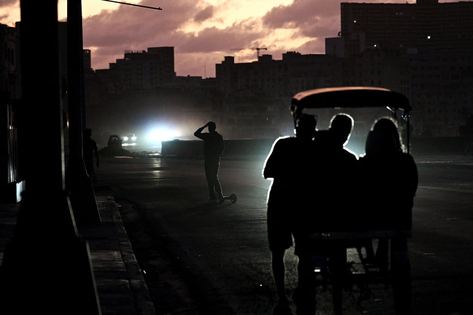 People transit on a street without power during a nationwide blackout in Havana, Cuba, on March 21, 2026.