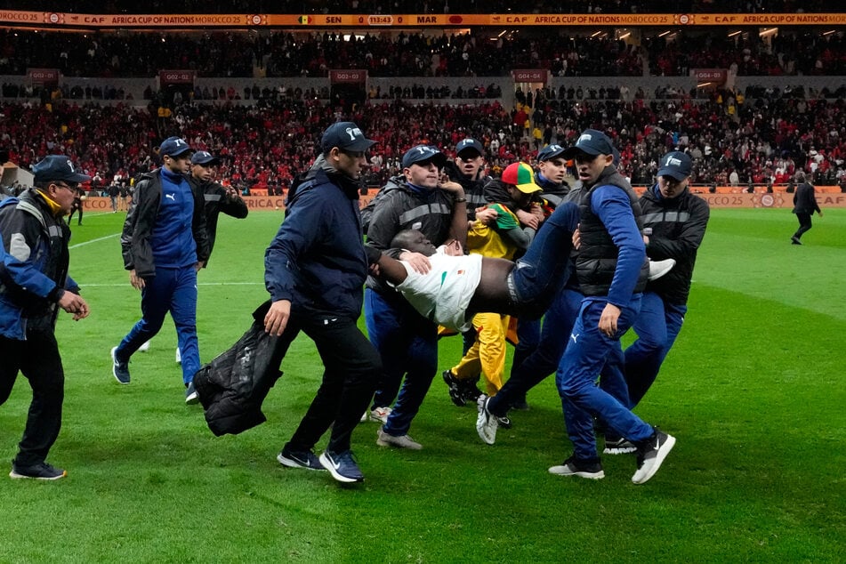 Mehrere Fans stürmten in der Unterbrechung auf den Platz und mussten von Sicherheitskräften heruntergetragen werden.