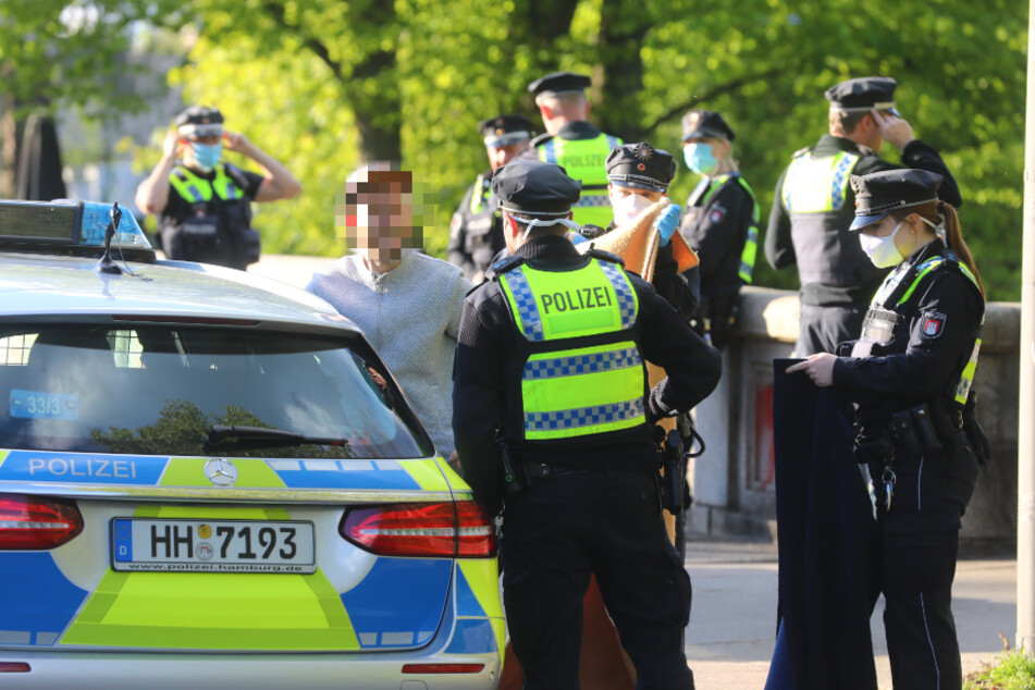 Polizisten sprechen mit einem jungen Mann, der Erste Hilfe geleistet hat.
