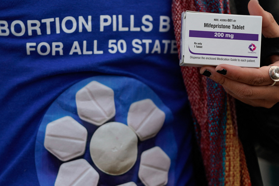 A pro-abortion rights activist holds a box of mifepristone during a rally in front of the US Supreme Court on March 26, 2024, in Washington, DC.