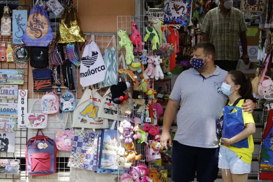 Zwei Personen mit Masken stehen vor einem Geschäft in der Innenstadt von Palma.