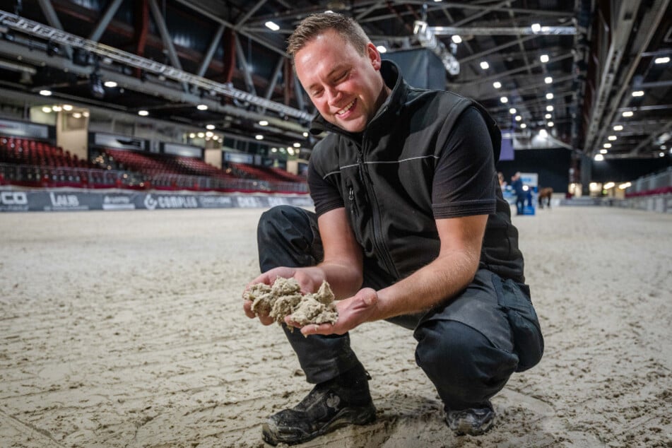 Bodenbauer Jan Henning Reiners (37) prüft einen Teil der 1050 Tonnen Sandgemisch, auf dem die Pferde reiten. Im Sand sind unter anderem geotextile Vliesstücke enthalten.