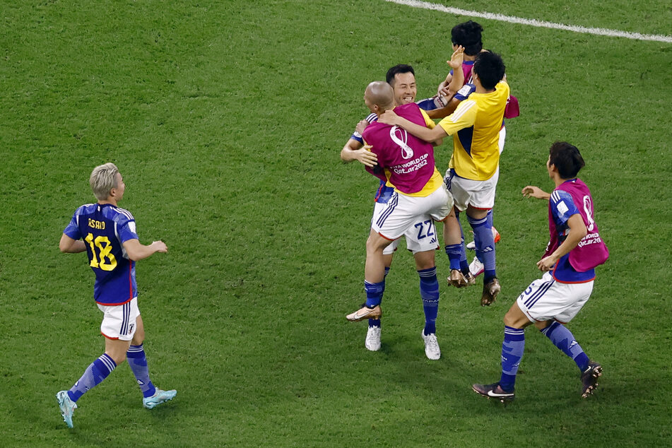 Japan's substitutes, led by Celtic forward Daizen Maeda (c.), storm the field at the end of their team's win over Spain.