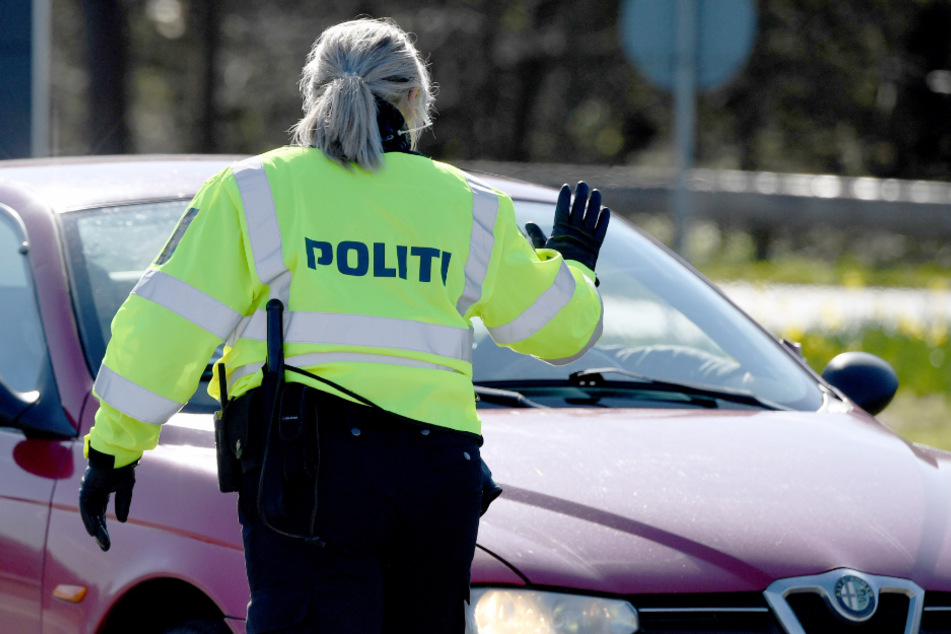 Eine Polizisten hält an der deutsch-dänischen Grenze ein Fahrzeug an.