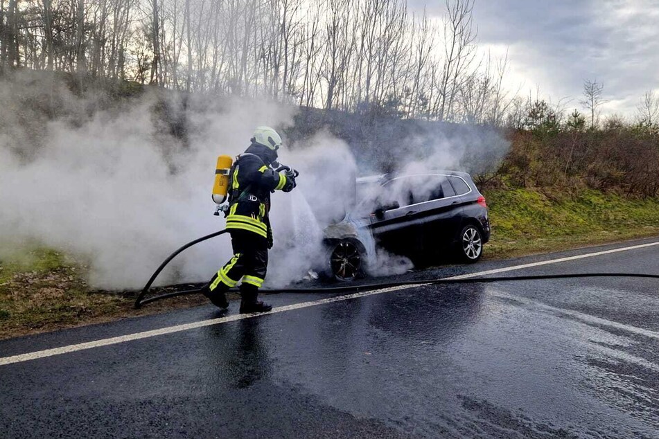 Die Feuerwehr löscht den brennenden BMW auf der B2 bei Michendorf in Brandenburg.