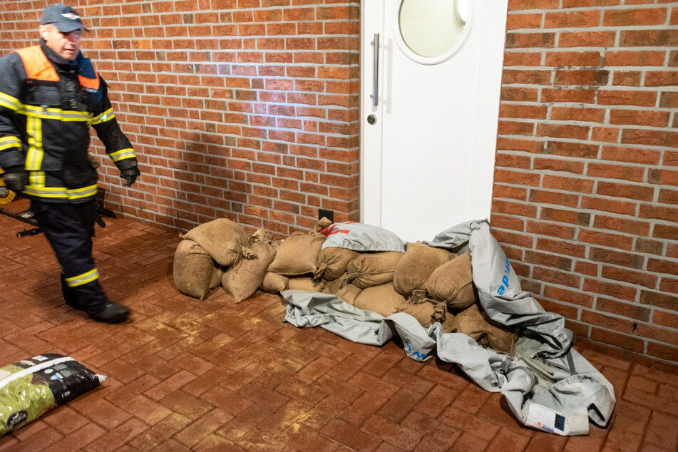 Feuerwehrleute und Anwohner versuchen Gebäude durch Sandsäcke zu schützen.