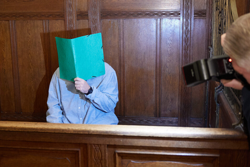 Der 39-jährige Angklagte sitzt im Landgericht Berlin und verbirgt sein Gesicht.