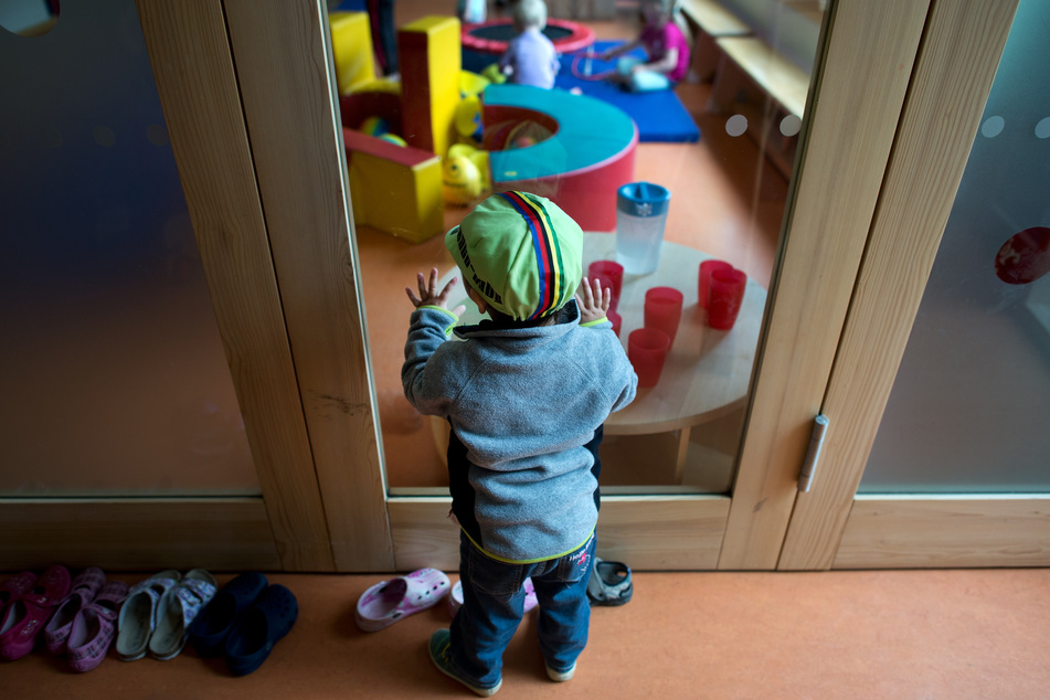 A young child stands on a glass panel in a nursery in Dresden and watches other children play. (File Image)