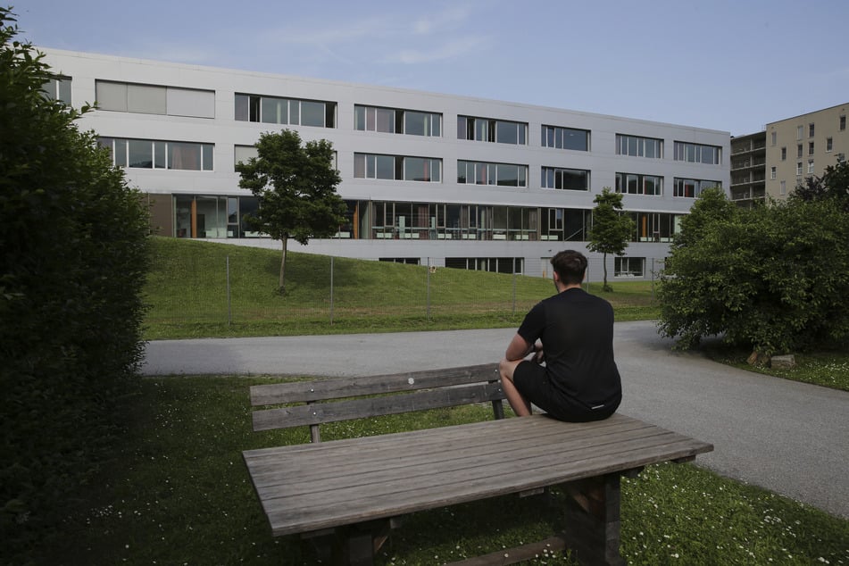 Ein Schüler sitzt auf einem Tisch vor der Schulgebäude und betet für die Opfer.