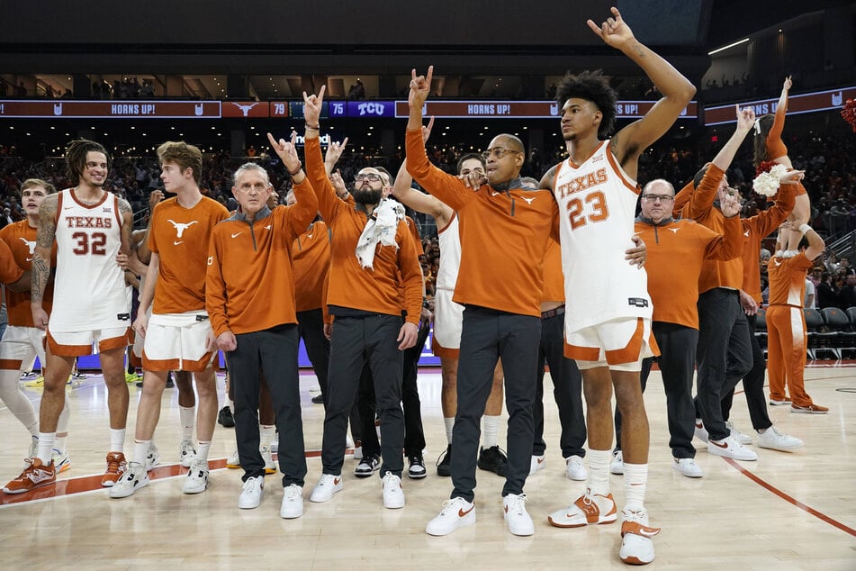 Texas Longhorns interim head coach Rodney Terry (center r) and players celebrate a victory over the TCU Horned Frogs at the Moody Center in Austin, Texas.