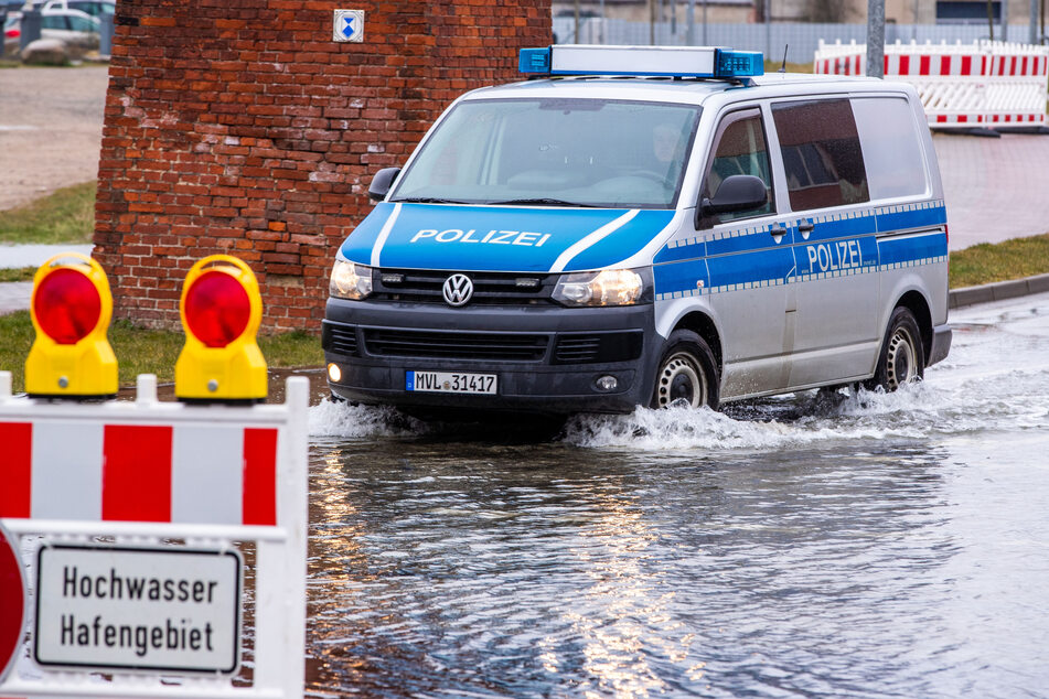 Ein Polizeiauto fährt über eine teilweise überfluteten Straßenkreuzung am Hafen in Wismar.