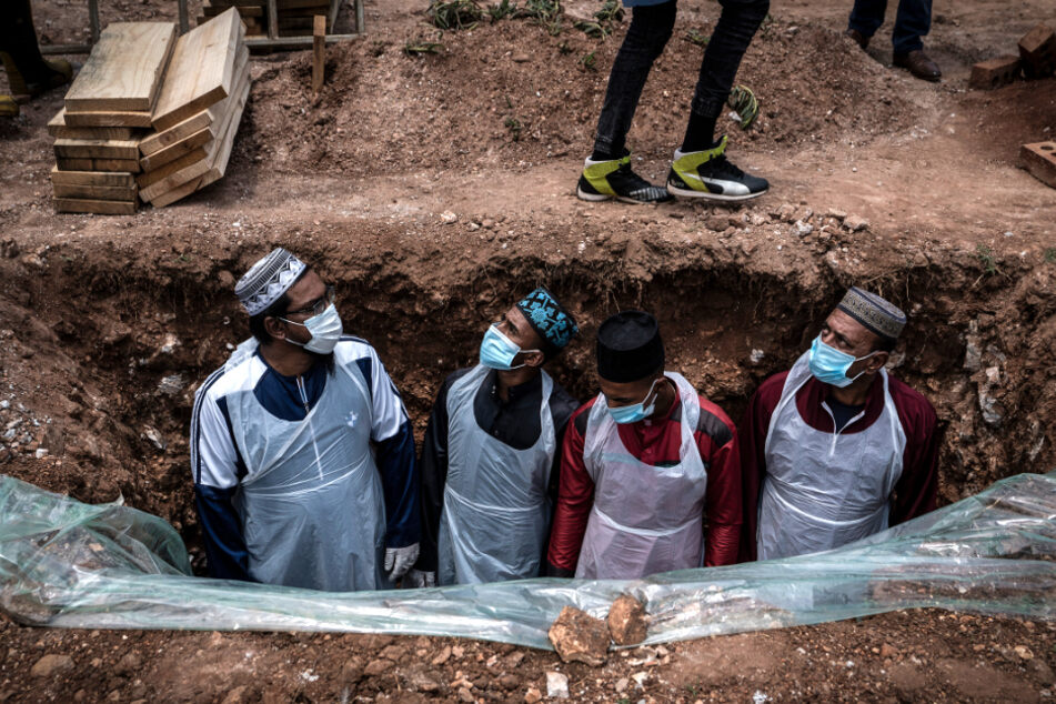 Johannesburg: Bestatter in Schutzkleidung bereiten das Grab für eine am Coronavirus verstorbene Person auf dem Avalon-Friedhof für die Beerdigung vor.