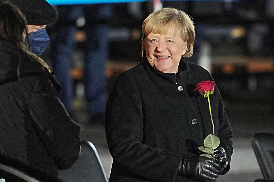 Bundeskanzlerin Angela Merkel (67, CDU) lacht nach ihrer Verabschiedung durch die Bundeswehr mit einer Rosen in der Hand neben ihrem Mann, Joachim Sauer (72).