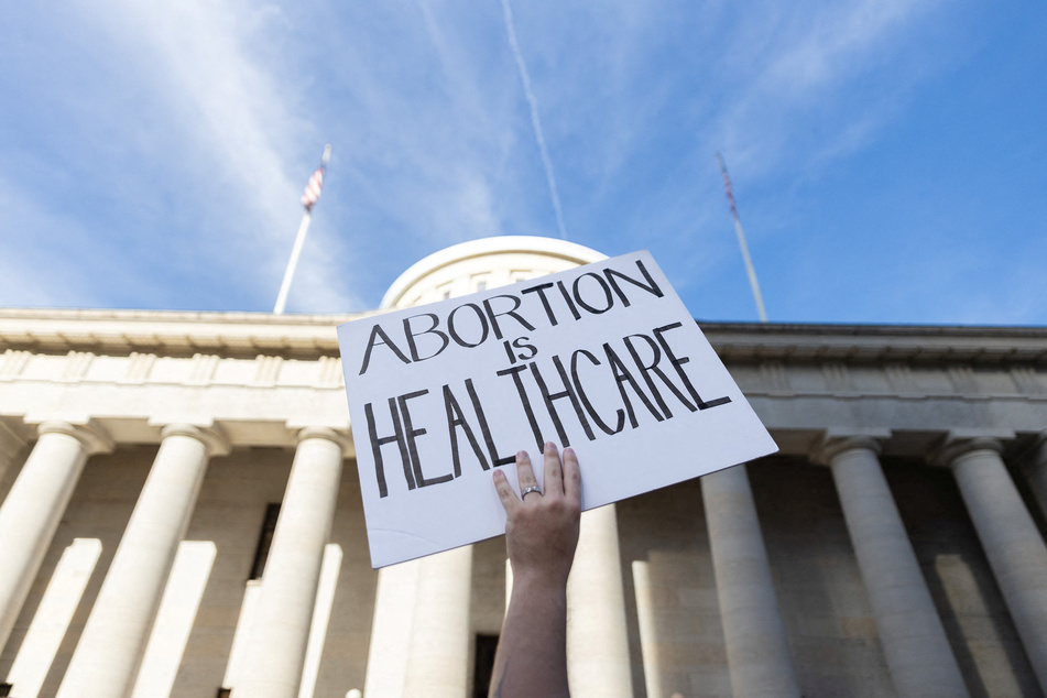 An abortion rights activist holds a sign reading "Abortion Is Health Care" outside the Ohio Statehouse.