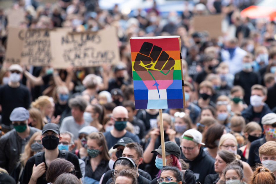 Teilnehmer einer Demonstration gegen Rassismus halten auf dem Neumarkt ein Schild mit einer geballten Faust, das sogenannte "Black Power"-Symbol.