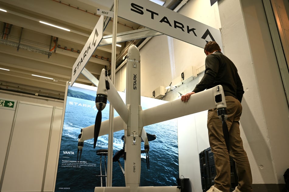 Ein Mitarbeiter von Stark Defence am Messestand seiner Firma mit einer Drohne vom Modell Virtus.
