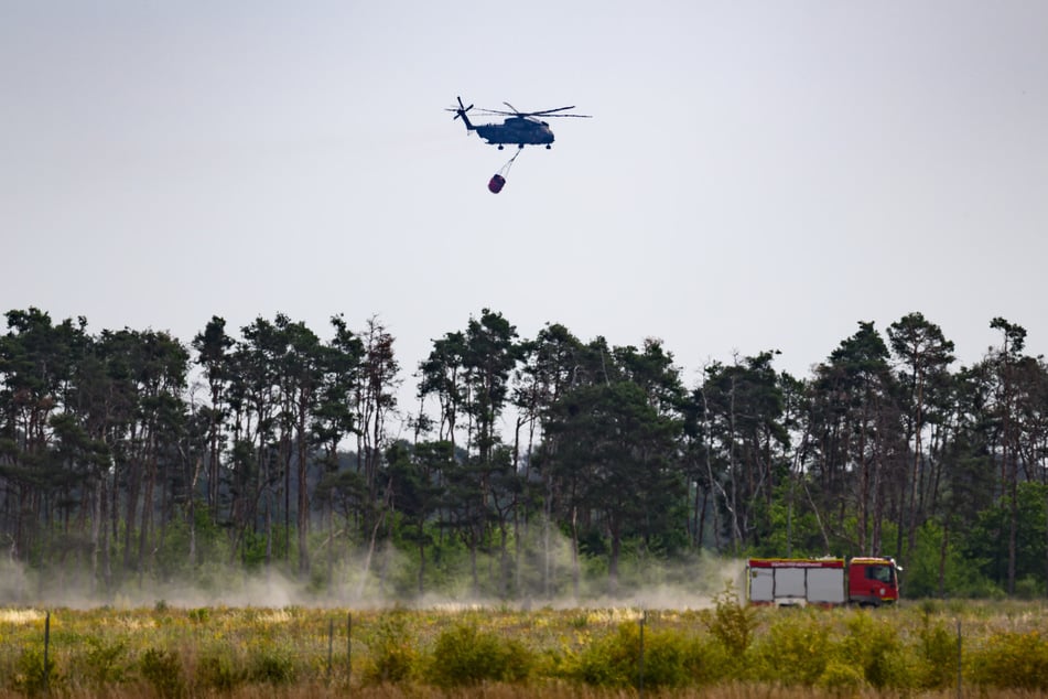 Ein Löschhubschrauber der Bundeswehr kreist über der Gohrischheide. In 230 Anflügen hatte er am Montag bereits rund eine Million Liter Wasser über dem Waldbrandgebiet abgeworfen.